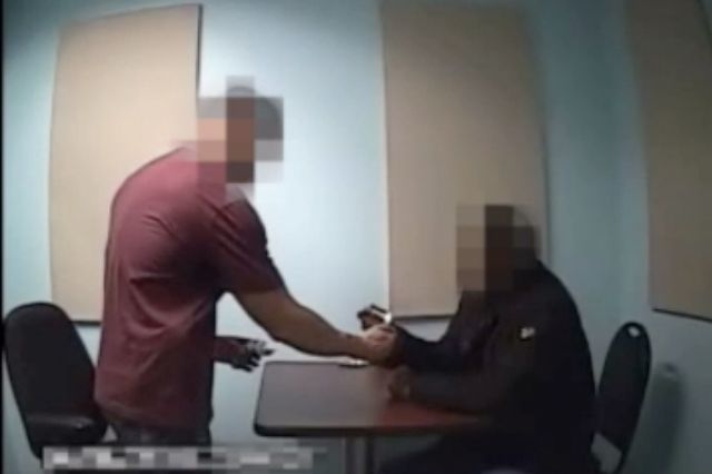 A still from an interrogation video obtained by The Appeal shows an NYPD officer lighting a cigarette for a man
